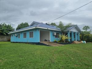 a blue house with a green lawn in front of it at Le Seraphine's Accommodation in Apia