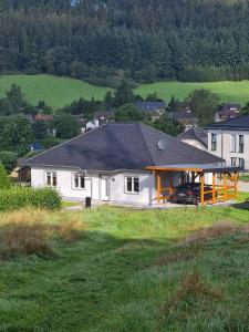 a white house with a black roof in a field at Ferienhaus am Berg in Hohenfels-Essingen