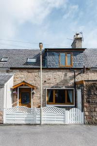 a stone house with a white fence at Mabels Cottage by the beach in Nairn