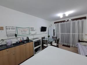 a kitchen and living room with a table and a kitchen and a room at Brusque Comfort Studios in Brusque