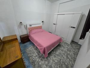 a small bedroom with a pink bed and a cabinet at Céntrico departamento en el Piso 1 in Tacna