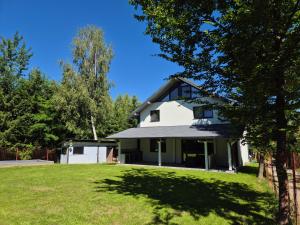 a white house with a grassy yard in front at Vila Yolo Valea Avrigului in Porumbacu de Sus