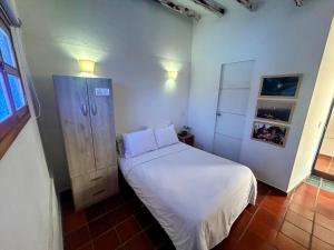 a small bedroom with a white bed and a cabinet at Zana Hotel Boutique in Bogotá