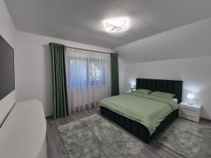 a bedroom with a green bed and a window at Vila Yolo Valea Avrigului in Porumbacu de Sus