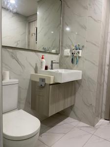 Un baño con lavabo, inodoro y espejo. en Masterise Vin, en Phú Thú