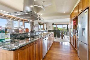 a large kitchen with wooden cabinets and stainless steel appliances at Alyeska farm house in Apollo Bay