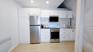 a kitchen with white cabinets and a stainless steel refrigerator at Dôme Le Scandinave in Brownsburg