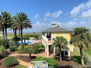 a yellow house with a swimming pool and palm trees at Open Airy Beautiful - Ocean AND Bay Views! in Galveston