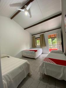 a bedroom with two beds and a ceiling fan at Pousada Mutary in Santa Cruz Cabrália