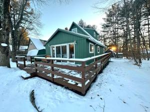 a green house in the snow with a fence at Lakefront with Lots of Light and Private Dock Access in Ferndale