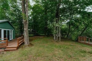 a house with a wooden deck in the woods at Lakefront with Lots of Light and Private Dock Access in Ferndale