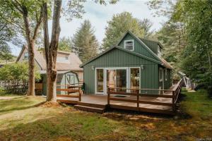 a green tiny house with a large porch at Lakefront with Lots of Light and Private Dock Access in Ferndale