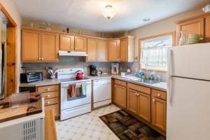 a kitchen with wooden cabinets and a white refrigerator at Lakefront with Lots of Light and Private Dock Access in Ferndale