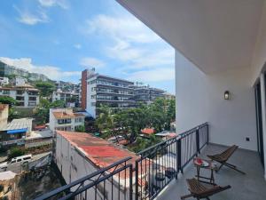 a balcony with chairs and a view of a city at Estudio de ensueño con alberca 303 in Puerto Vallarta