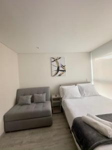 una camera da letto con un letto e un divano di Encanto y ubicación perfecta en Corferias a Bogotá