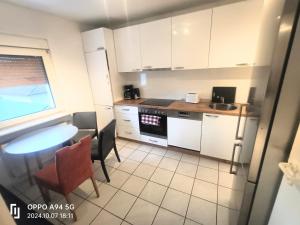 a small kitchen with white cabinets and a table at FMI 66 Next to Airport in Mörfelden-Walldorf