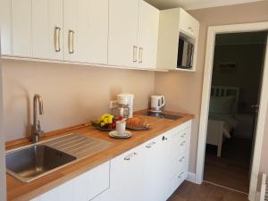 a kitchen with white cabinets and a bowl of fruit on the counter at Haus Wellenrauschen in Zingst +12 photos