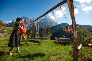 a woman holding a child on a swing at Appartamenti Maierhof in La Valle