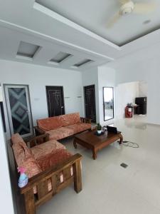 Una sala de estar con sofás y una mesa de café. en Mengkuang Villa - Family Deluxe Room, en Kampong Mangkok