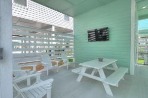 a patio with white chairs and a table and a tv at Turtle Cove in Rockport