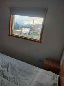 ventana en un dormitorio con cama y camión en Apart El Rosado, en El Chaltén