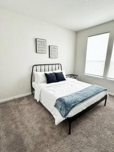 a bedroom with a bed with white sheets and blue pillows at The White Haus A Cozy New Braunfels Cottage in New Braunfels