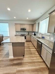 a large kitchen with wooden floors and stainless steel appliances at The White Haus A Cozy New Braunfels Cottage in New Braunfels