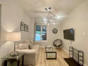 a living room with a white couch and a tv at Stylish 3-bdrm suite w free Parking in Kitchener