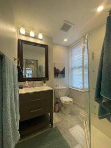 a bathroom with a sink and a toilet and a mirror at Stylish 3-bdrm suite w free Parking in Kitchener +23 photos