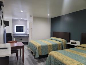 une chambre d'hôtel avec deux lits et une table dans l'établissement Motel Moonlight, à Anaheim