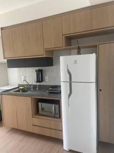 a kitchen with a white refrigerator and wooden cabinets at 2307 Uwin Brooklin melhor custo benefício ao lado do metrô in Sao Paulo