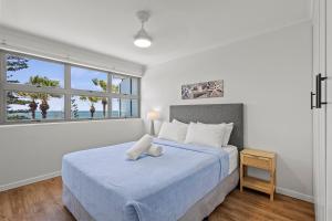 una camera da letto con un grande letto con una coperta blu di Malibu Apartments a Mooloolaba Altre 37 foto