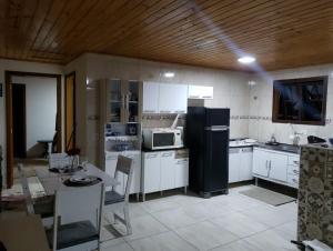 a kitchen with white cabinets and a black refrigerator at Casa do Aconchego in Campos do Jordão +30 photos