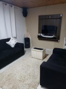 a living room with a couch and a flat screen tv at Casa do Aconchego in Campos do Jordão