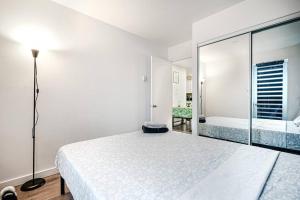 a white bedroom with a bed and a mirror at Bienvenue dans votre havre de paix à Griffintown in Montréal
