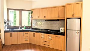 une cuisine avec des armoires en bois et un réfrigérateur blanc dans l'établissement Cottonwood Villa Rotensia BBQ Pool Pingpong, à Bandung