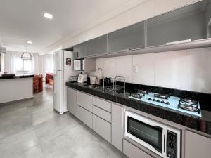 eine Küche mit weißen Schränken und einem weißen Kühlschrank in der Unterkunft Casa para temporada em Arraial D'ajuda in Porto Seguro