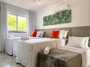 2 Betten in einem Hotelzimmer mit orangefarbenen Kissen in der Unterkunft Casa para temporada em Arraial D'ajuda in Porto Seguro + 33 Fotos