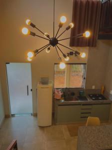 cocina con lámpara de araña y nevera en Claruá Chalés - LOFT CAJU- Lofts românticos em Cavalcante 5m do centro, en Cavalcante