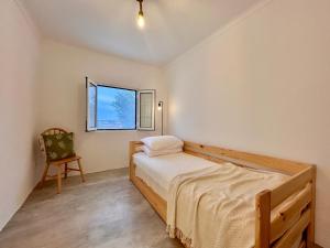 Un dormitorio con una cama y una silla y una ventana. en Casa Valentina, en Pedrógão