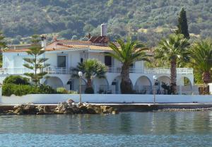 a large white house with palm trees in front of the water at Manthos in Kalloni