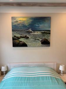 a painting hanging on a wall above a bed at Old Center Apartment in Liepāja
