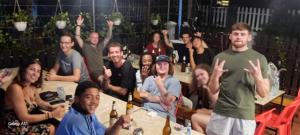 a group of people sitting at tables with their hands up at Aurora Backpackers Hostel in Luang Prabang