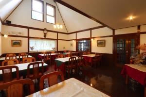a dining room with tables and chairs and windows at Pension Angelica in Minami Aso