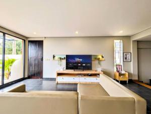 un salon avec un canapé et une télévision à écran plat dans l'établissement Cottonwood Villa Zamrud - Pingpong BBQ Pool Disney, à Tegalharendong
