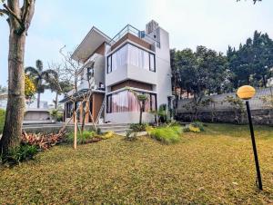 une maison blanche avec un arbre dans une cour dans l'établissement Cottonwood Villa Zamrud - Pingpong BBQ Pool Disney, à Tegalharendong