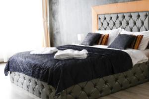a bedroom with a large bed with black sheets and blue pillows at All Homes by Nati in Braşov
