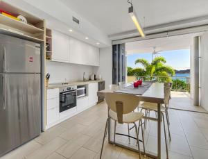 Nelly Bayにある1 Bright Point Apartment 2204の白いキャビネットとテーブルと椅子のあるキッチン