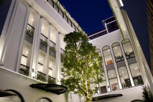 a white building with a tree in front of it at Indigen Boutique Hotel Cao Bang in Cao Bằng