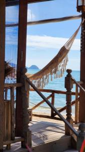a hammock on a porch overlooking the beach at Castaway Beach Bungalows in Srithanu